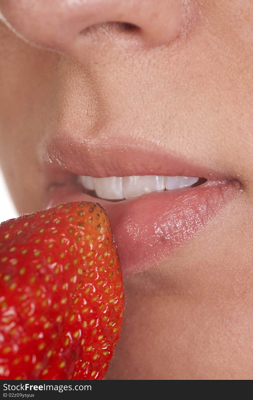 A close up of a womans lips with a red ripe strawberry. A close up of a womans lips with a red ripe strawberry.