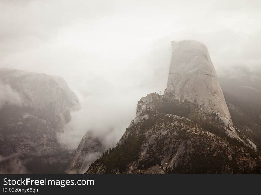 Half Dome peeking through the clouds as seen from Washburn Point in Yosemite National Park, California. Half Dome peeking through the clouds as seen from Washburn Point in Yosemite National Park, California.