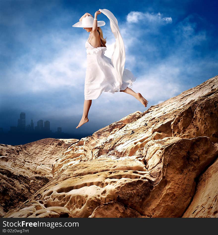 Beautiful girl in White on the mauntain under sky with clouds