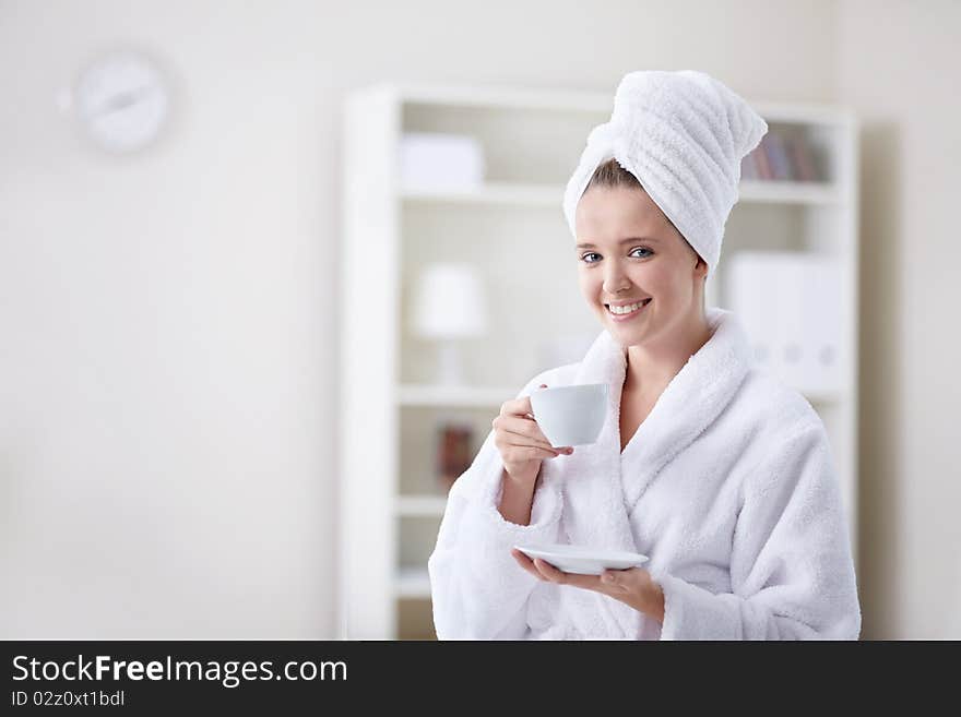 Beautiful girl in a bathrobe and a towel keeps the cup. Beautiful girl in a bathrobe and a towel keeps the cup