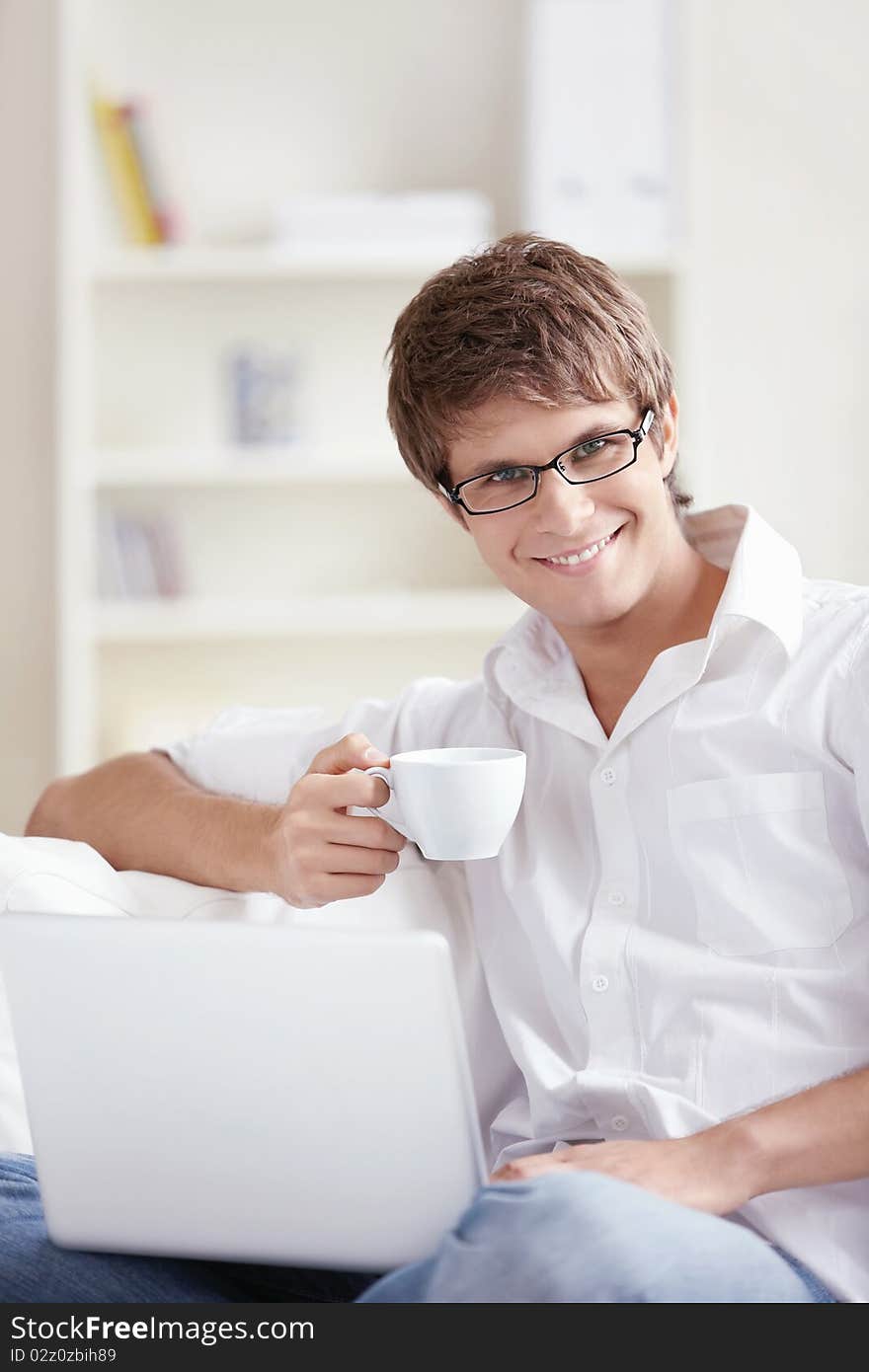 Attractive young man with a cup and laptop. Attractive young man with a cup and laptop