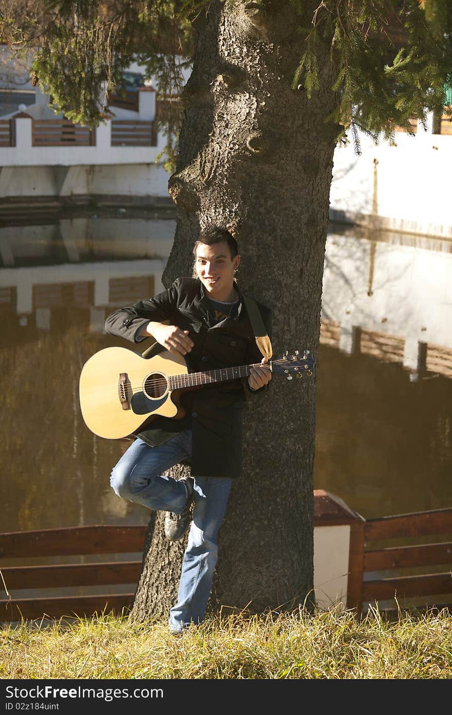 Happy man playing guitar on the middle of nature, under a tree. Happy man playing guitar on the middle of nature, under a tree