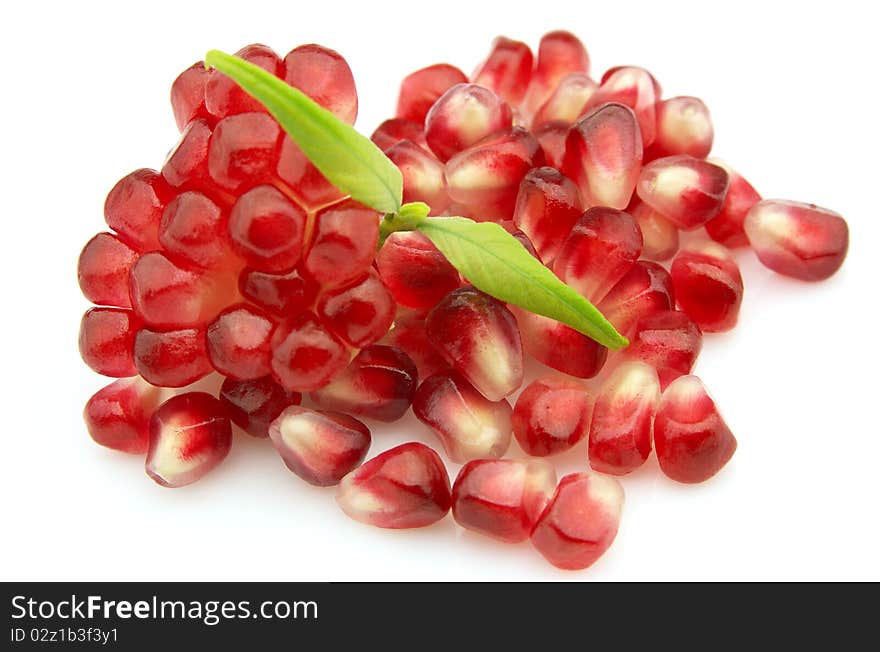 Grains of a pomegranate with a leaf on a white background