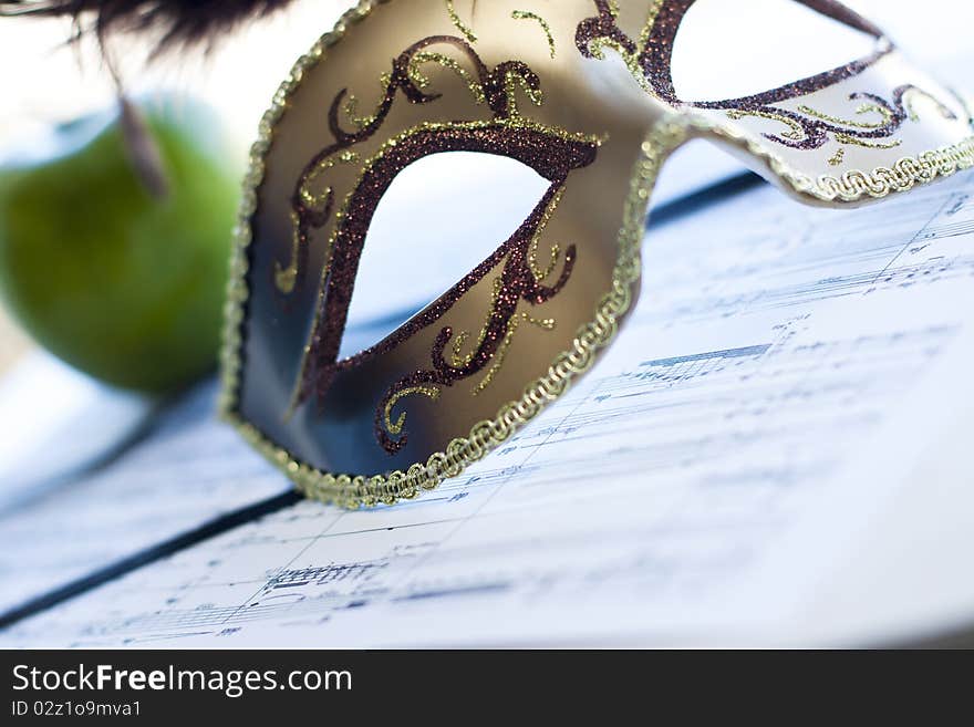 Venetian mask on the score and apple. Venetian mask on the score and apple