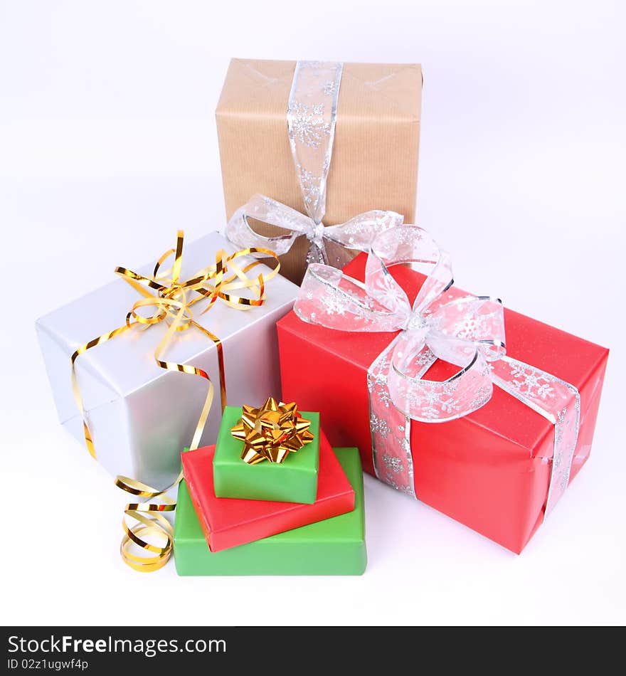 Gifts in silver, green, brown and red wrapping with bows on white background