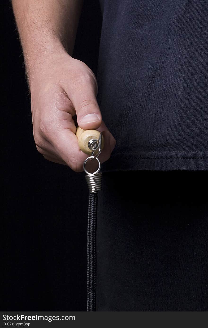 Human hand holding a jump rope on a black background.