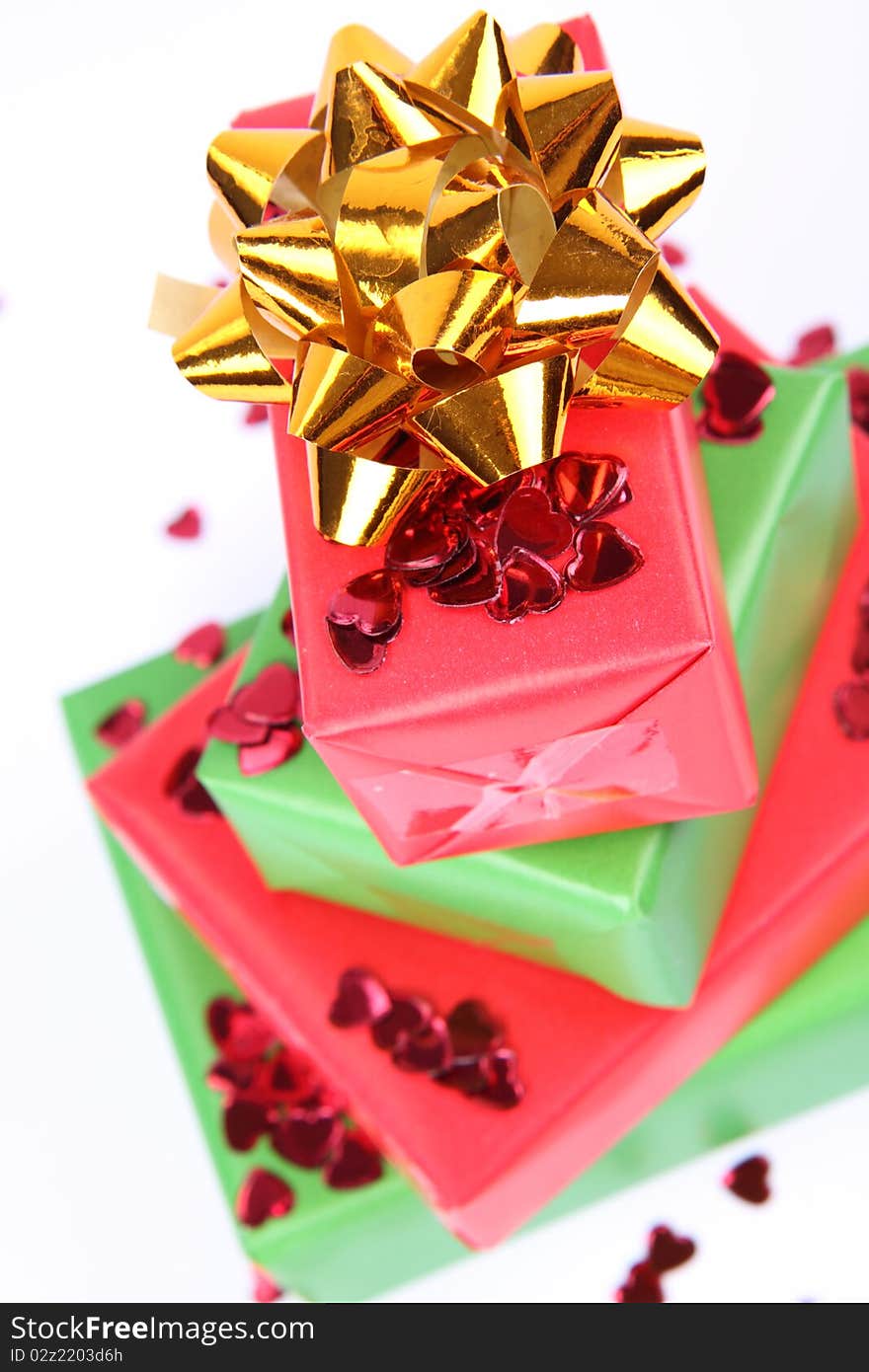 Gifts in green and red wrapping with a golden bow decorated with heart shaped confetti. Gifts in green and red wrapping with a golden bow decorated with heart shaped confetti