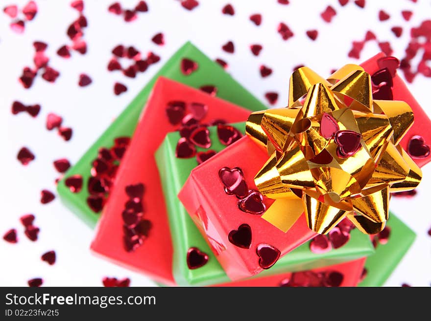 Gifts in green and red wrapping with a golden bow decorated with heart shaped confetti. Gifts in green and red wrapping with a golden bow decorated with heart shaped confetti