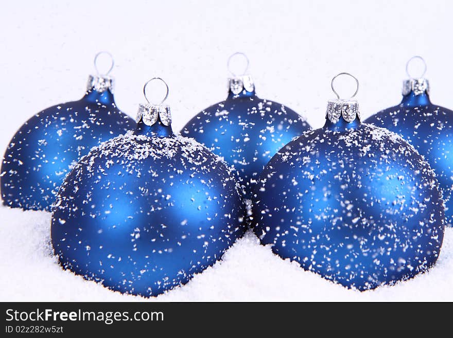 Blue matt christmas balls on snow and with snow falling on white background. Blue matt christmas balls on snow and with snow falling on white background