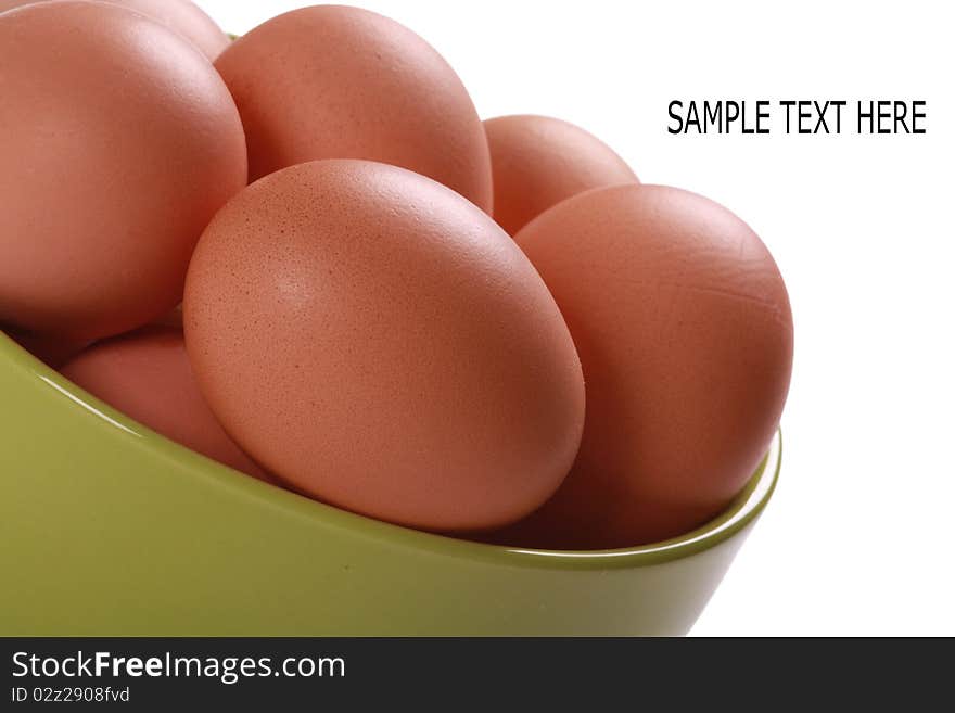 Fresh brown eggs in green bowl. Isolated over white