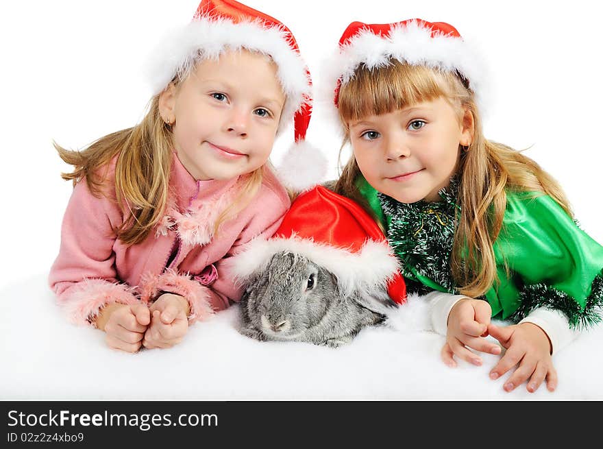 Two smiling girls with a rabbit in caps of Santy. Two smiling girls with a rabbit in caps of Santy