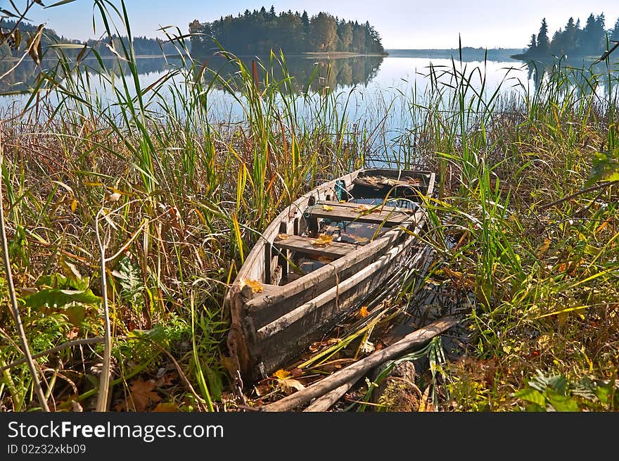 Old wooden boat on lake in the autumn