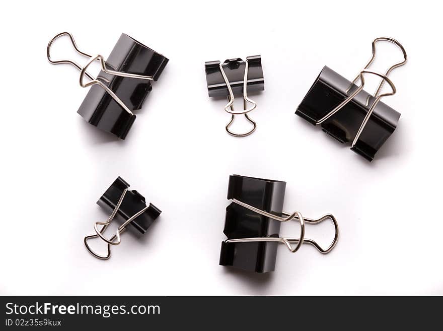 5 binder clips in in different positions and in different lighting with shadows on the white