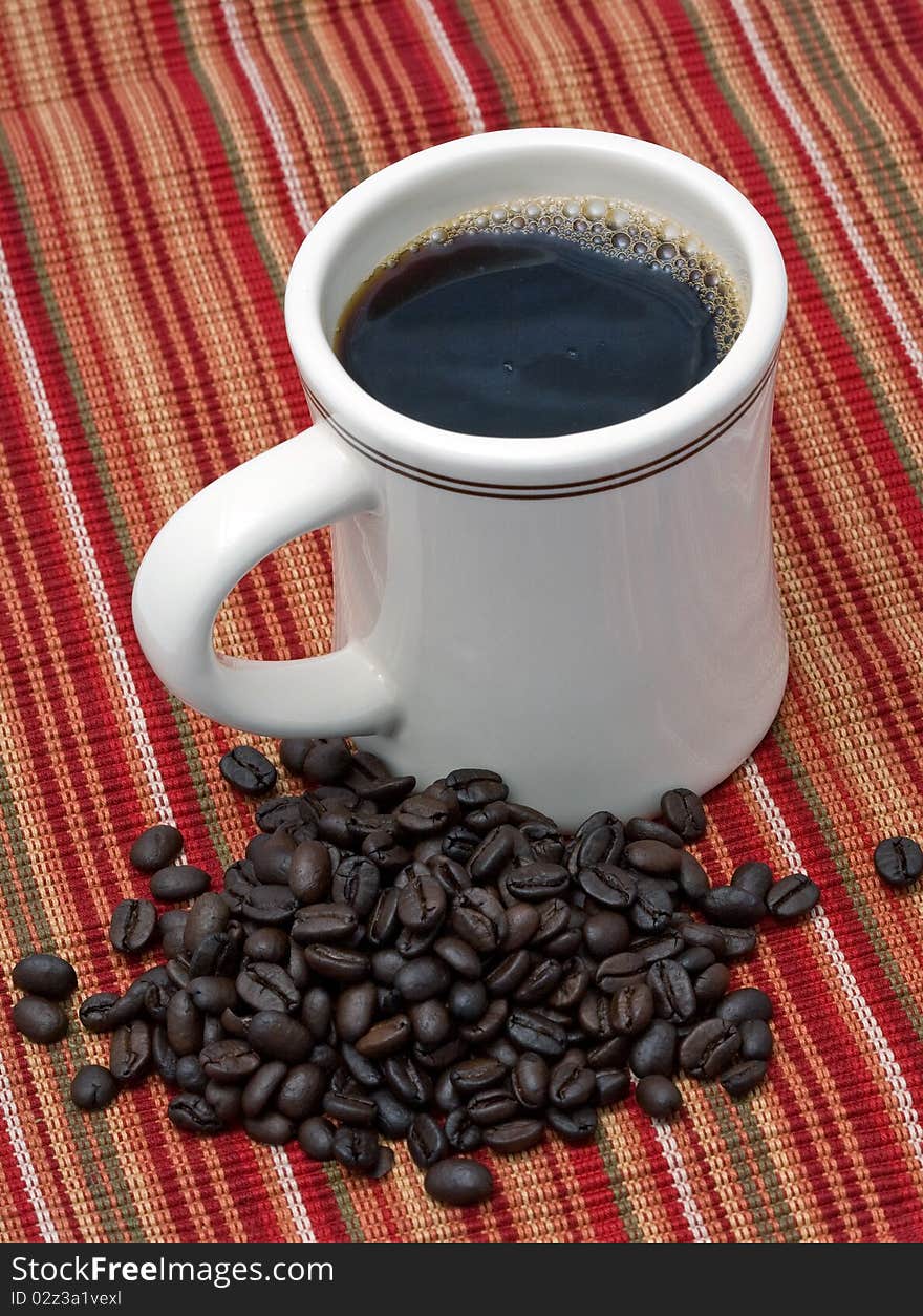 Cup of coffee next to pile of coffee beans