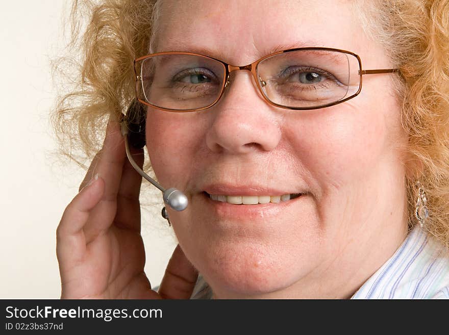 A mature woman taking a call on a hands free telephone headset. A mature woman taking a call on a hands free telephone headset