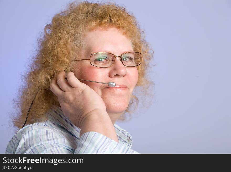 A mature woman taking a call on a hands free telephone headset. A mature woman taking a call on a hands free telephone headset