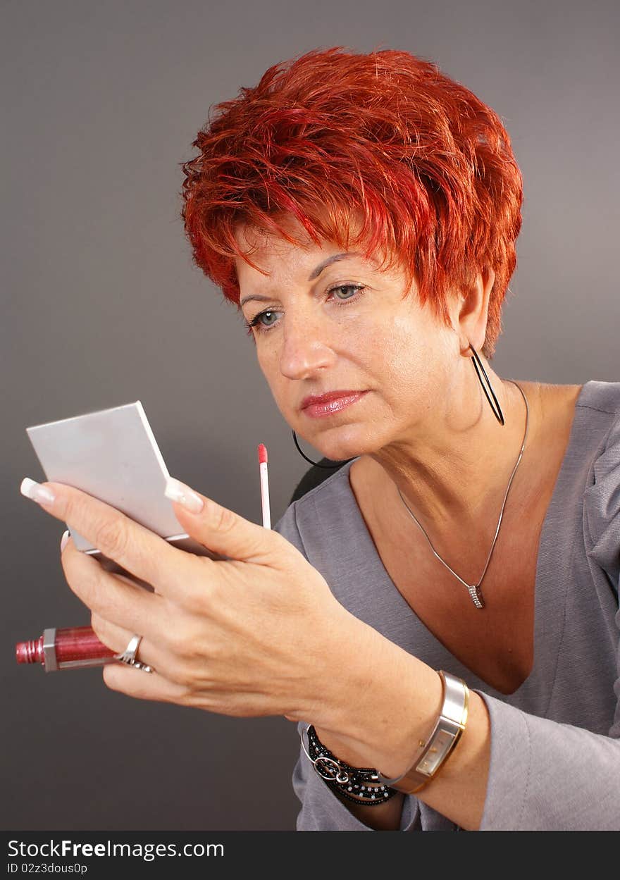 Beautiful woman with mirror on gray