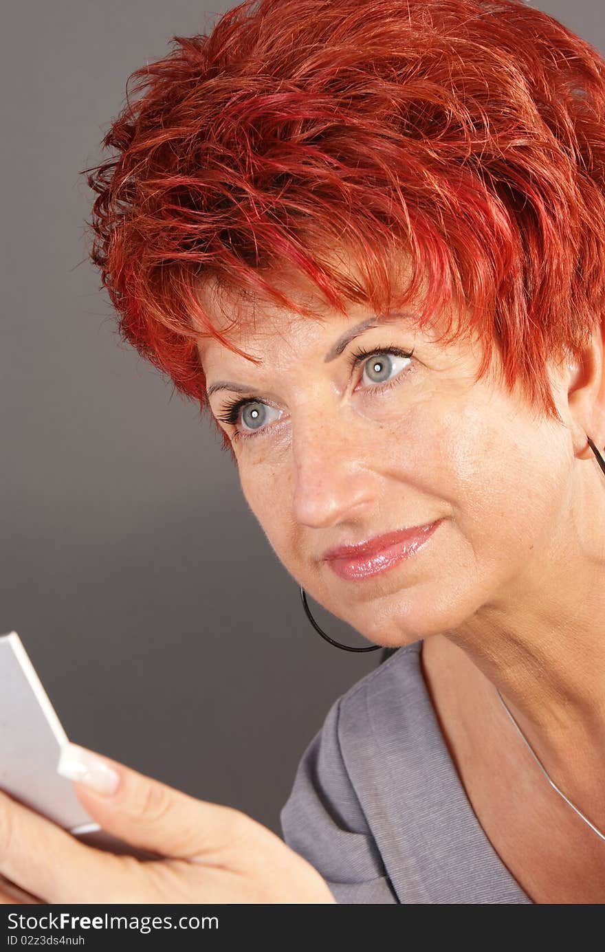 Beautiful woman with mirror on gray background