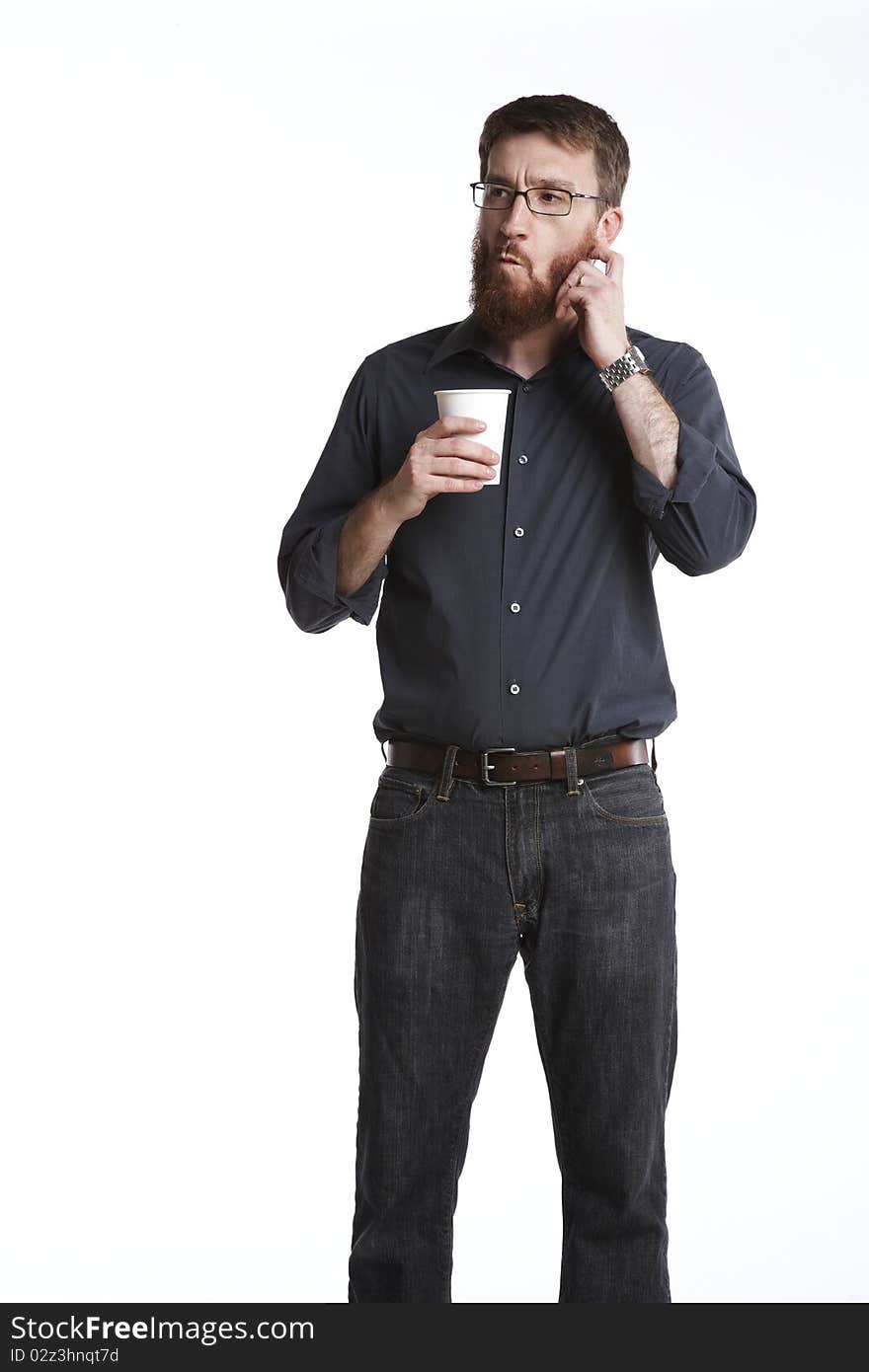 Man with beard in casual attire holding a paper coffee cup scratches his beard and makes a funny face. Man with beard in casual attire holding a paper coffee cup scratches his beard and makes a funny face