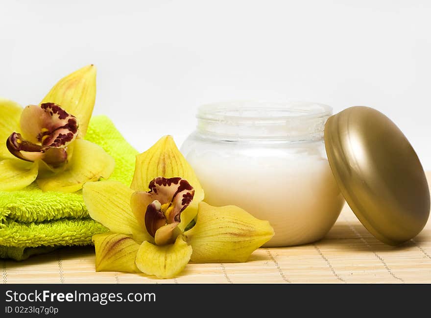 Spa essentials, cream and towel with yellow orchids