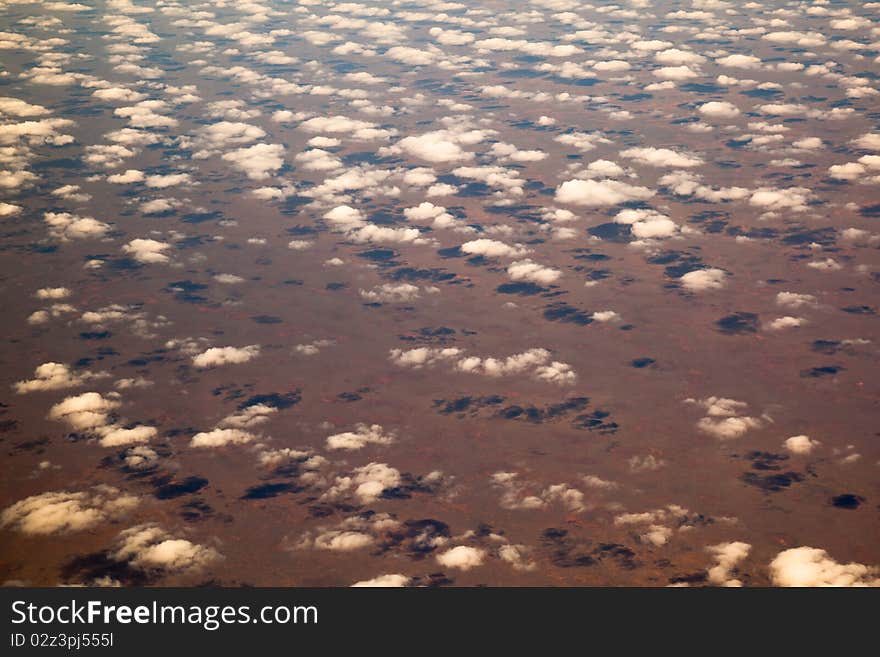 Popcorn clouds from the air over a orange desert landscape