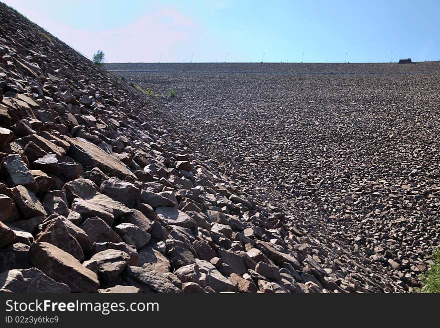 Slope of water dam built by stone, shown as construction and industrial solid and powerful. Slope of water dam built by stone, shown as construction and industrial solid and powerful.