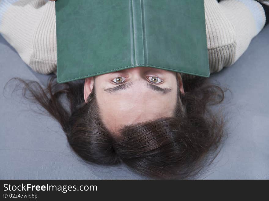 Long-haired man lies with book on his face. Long-haired man lies with book on his face