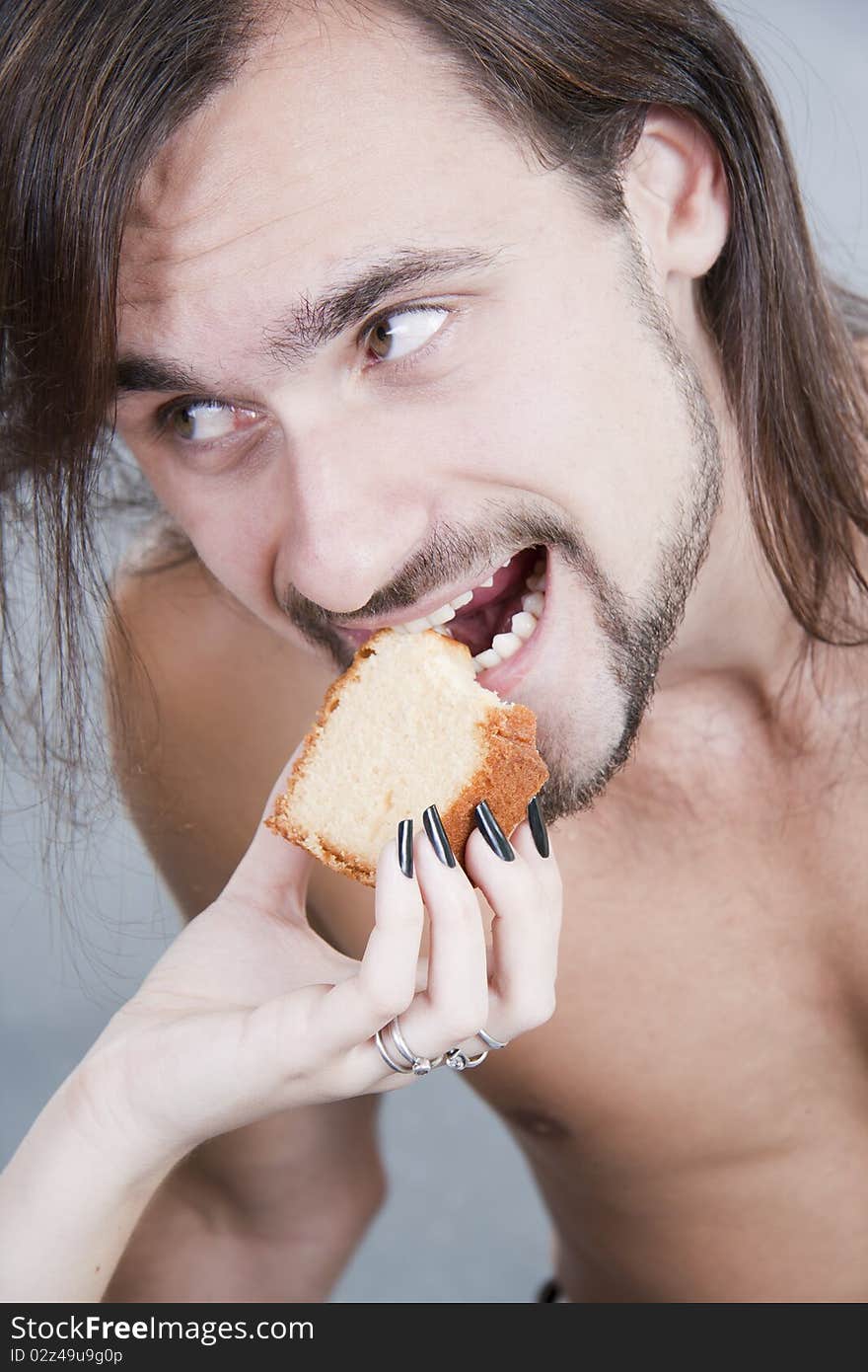 The young man eats a cake from female hands