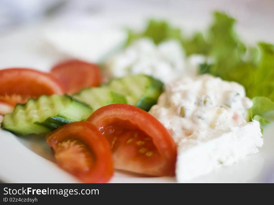 Salad , several kinds mixed in one plate with lettuce, tomatoes, cucumber and cheese on served decorated table background