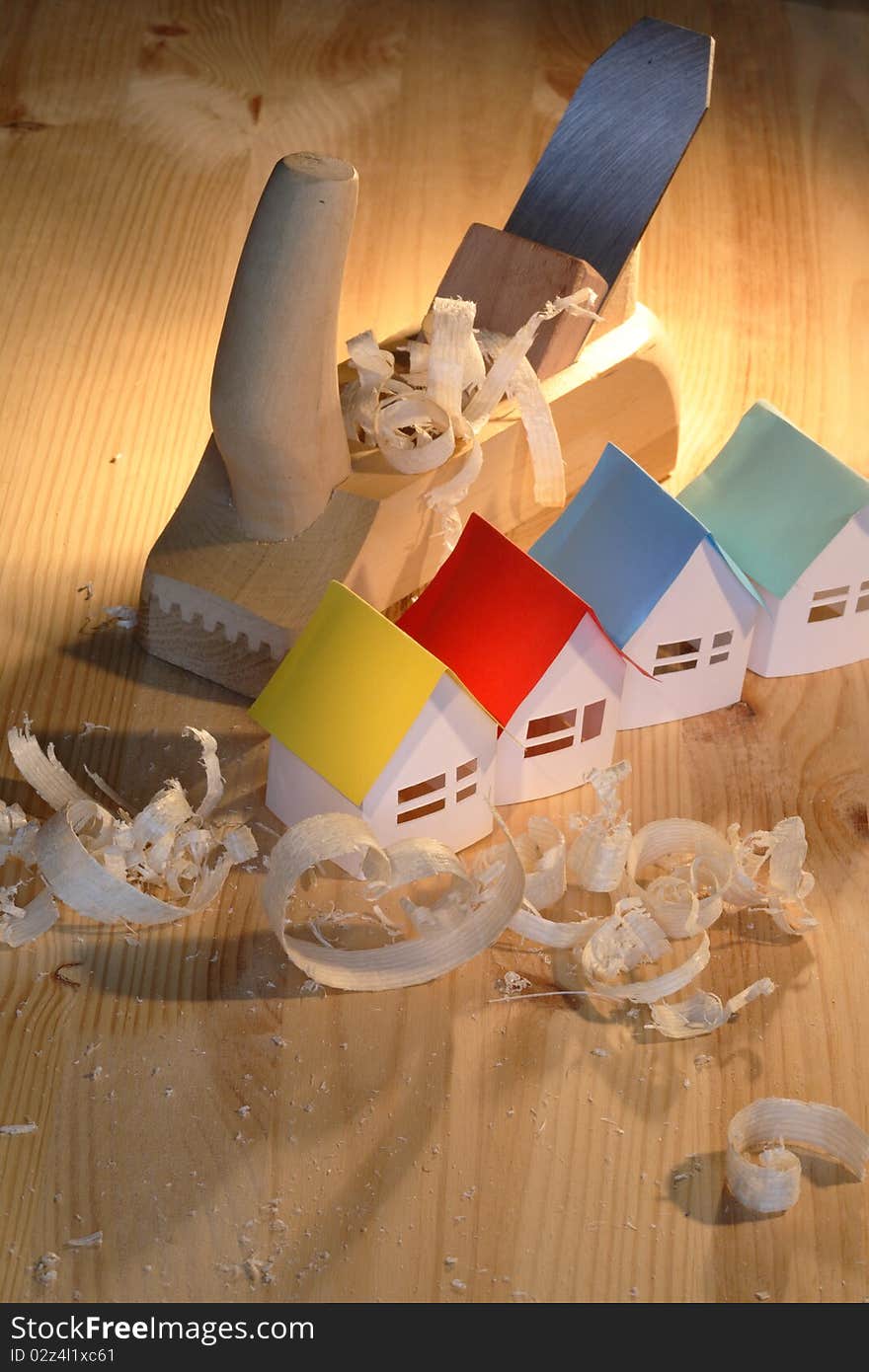 Few small paper houses near wood planer on wooden background. Few small paper houses near wood planer on wooden background