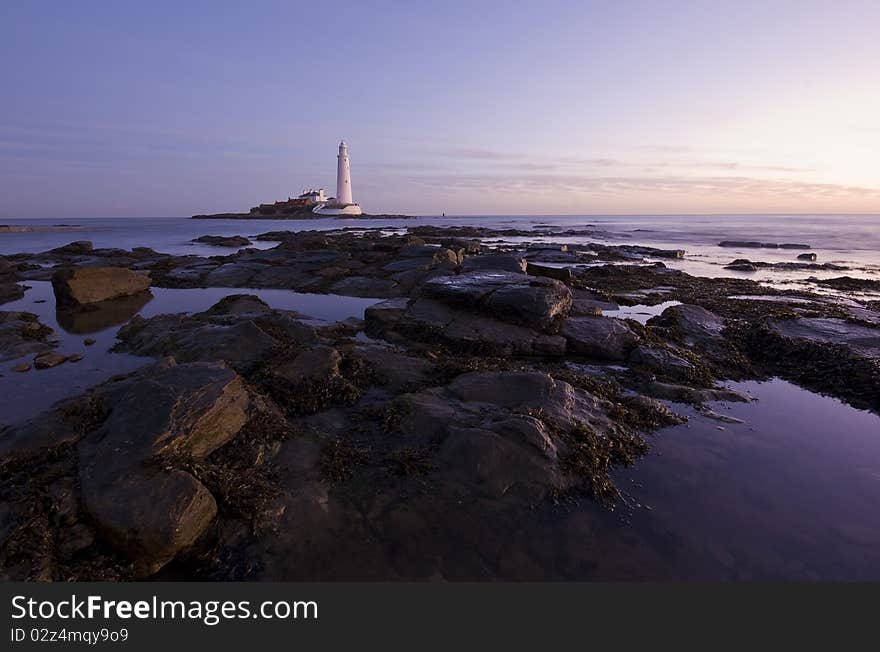 The lighthouse at sunrise in purple/pink colors. The lighthouse at sunrise in purple/pink colors