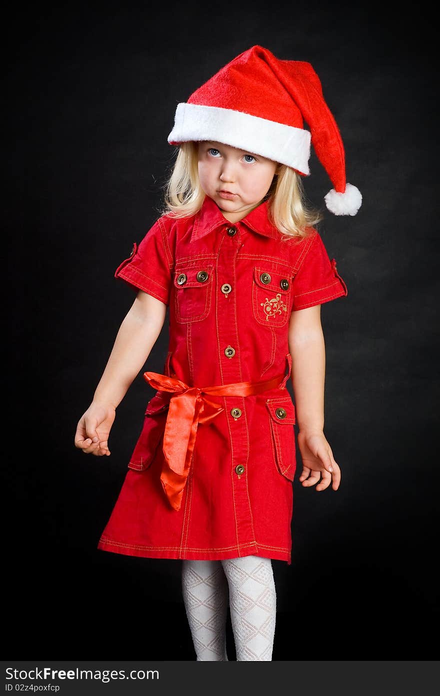 Displeased girl in red dress and santa cap