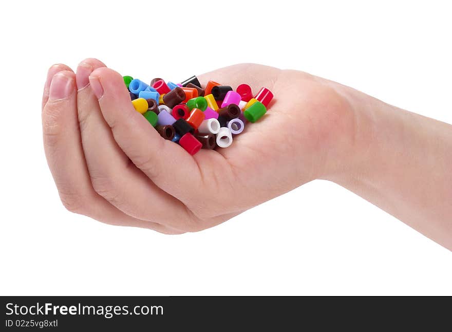 Plastic colorful mosaic particles in the child hand isolated over white background. Plastic colorful mosaic particles in the child hand isolated over white background