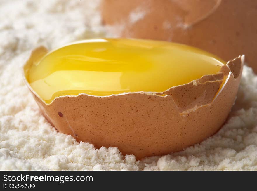 Broken eggshell and yolk in the flour macro shot. Broken eggshell and yolk in the flour macro shot