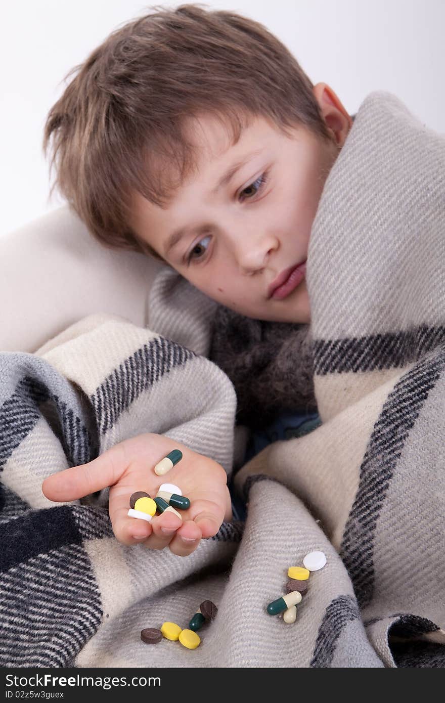 The ill boy holds a handful of tablets