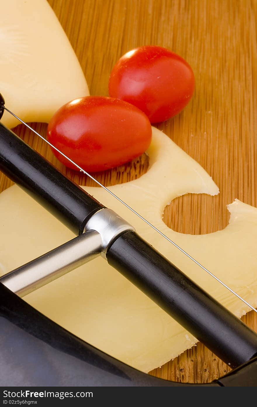 Swiss cheese slice and red tomato on a wood desk.