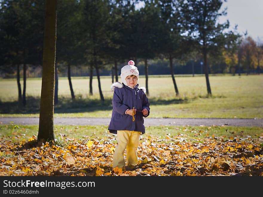 Little girl standing in the autumn park