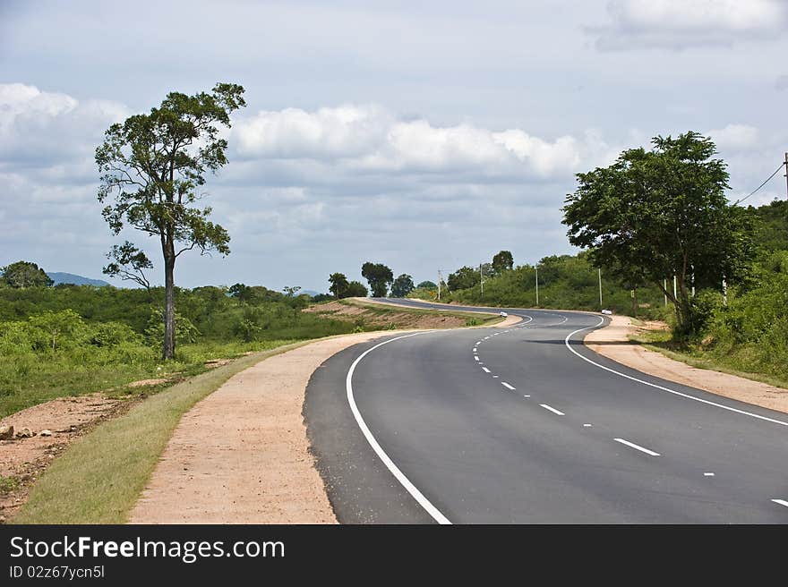 S shaped road running to the horizon with the clouds over it