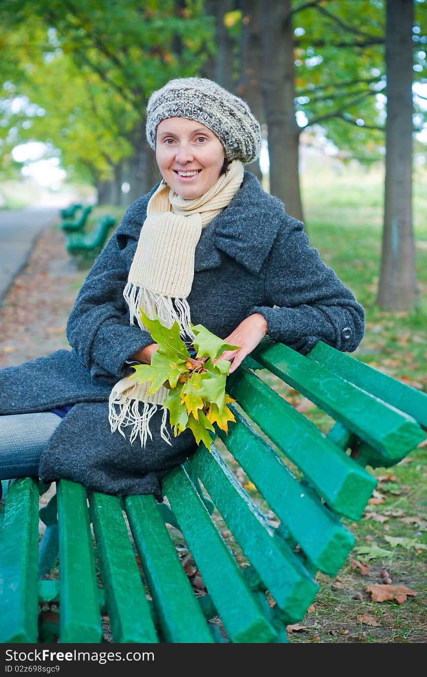 Pretty young woman resting on a bench in autumn park