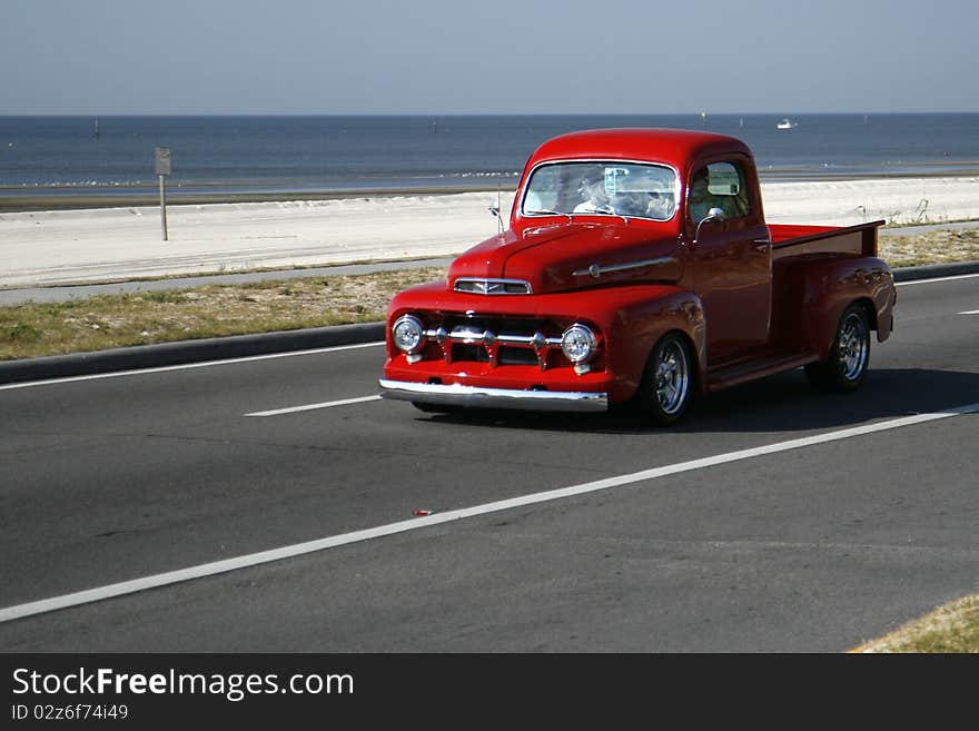 Old red ford pickup truck driving on beach highway. Old red ford pickup truck driving on beach highway.