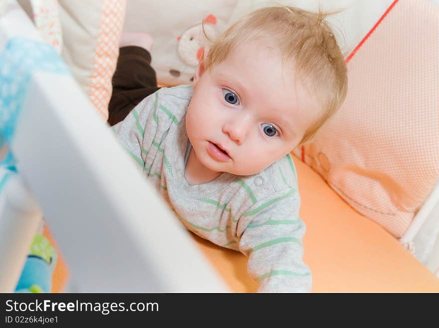 Baby lying in the latticed bedsted and look around. Baby lying in the latticed bedsted and look around