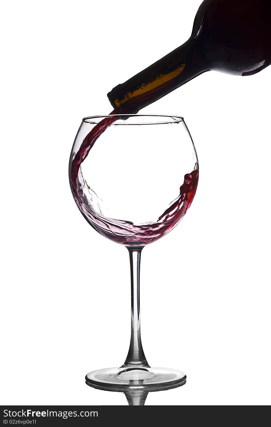 Pouring red wine in a glass of white background