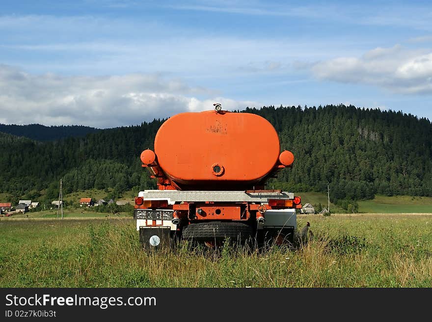 Green field - Mountain Landscape. Orange machine to irrigate