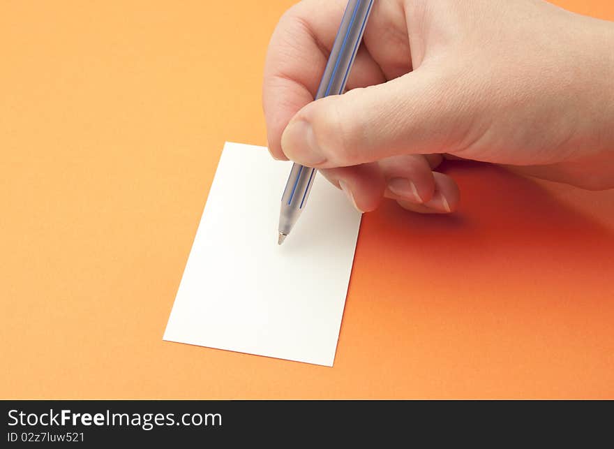 female hand with a pen on an orange background