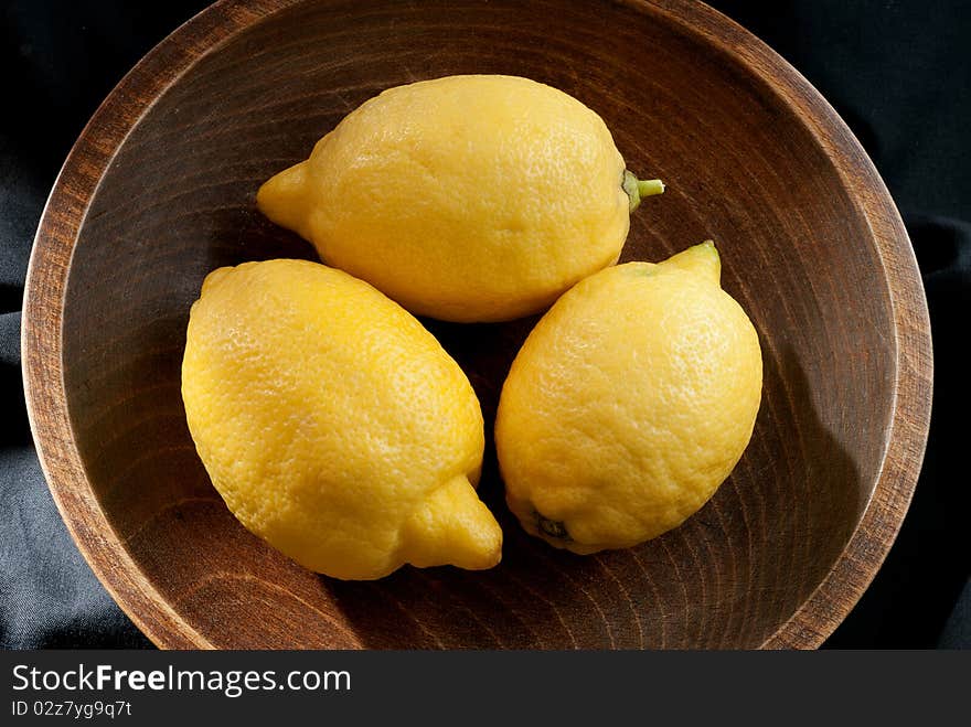 Three lemons in a wooden bowl