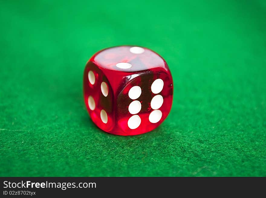 Single red dice on green background