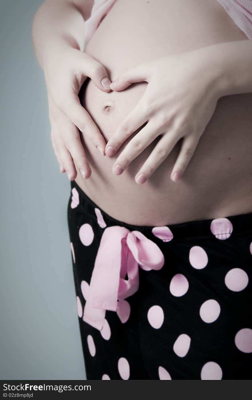 Two hands make a heart on pregnant belly on black. Two hands make a heart on pregnant belly on black