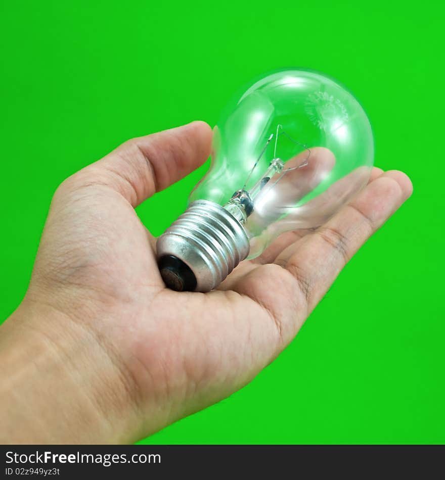 Lightbulb in a hand isolated on green background. Lightbulb in a hand isolated on green background.