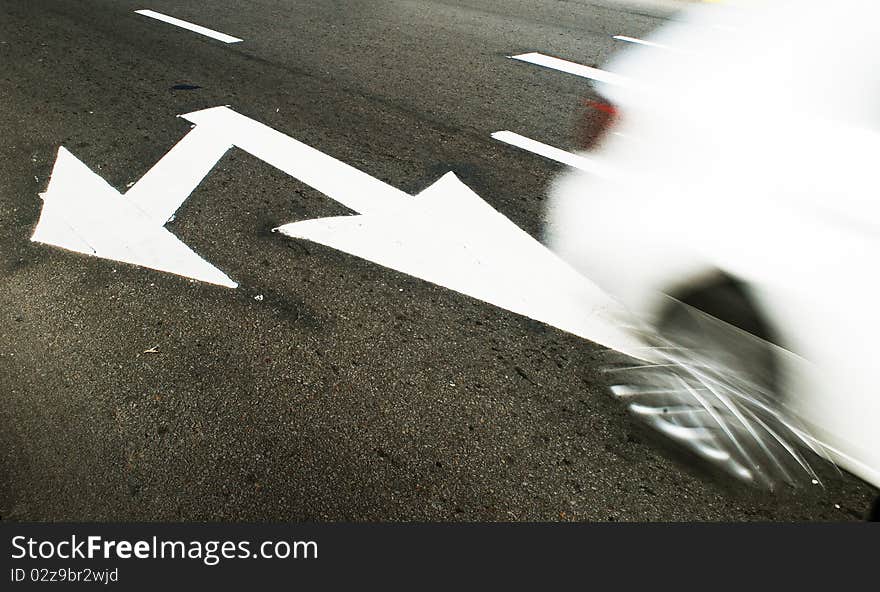 White arrow sign painted on pavement with blur white car. White arrow sign painted on pavement with blur white car