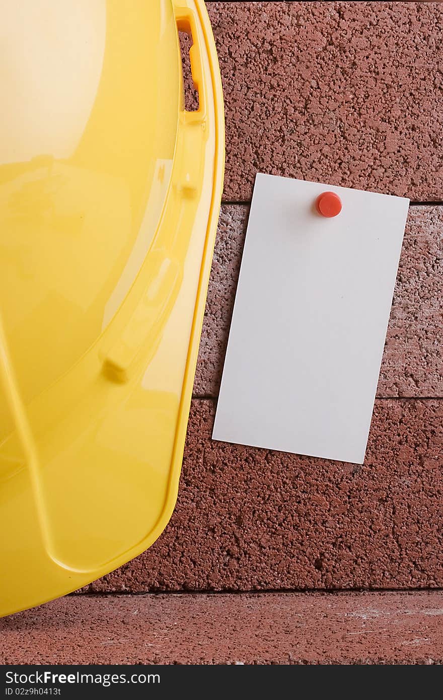 White piece of paper next to a yellow hard hat. Add your text to the paper. White piece of paper next to a yellow hard hat. Add your text to the paper.